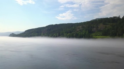 Beautiful aerial drone shot of the fogged riverside with a blue sky
