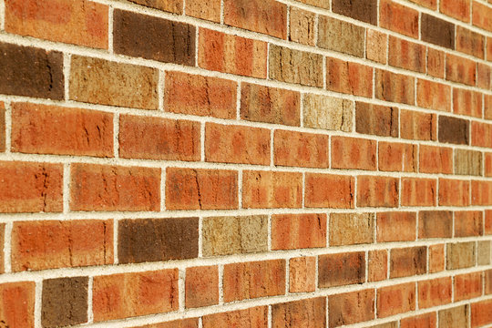 Angle view of a vintage brown multi-tone brick wall background with Flemish stretcher bond brickwork pattern
