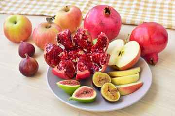 A plate of fresh fruits with pomegranate, apples, and figs, delicious fruit dessert.