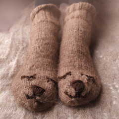 Cozy Winter fall autumn lifestyle: woman feets legs in warm cute bear socks. Retro toning, beige monochrome, hipster still life