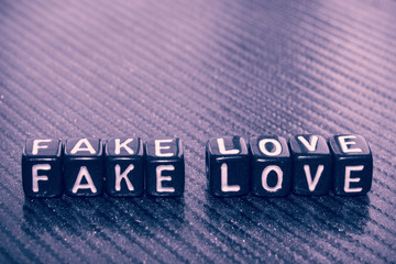 the words fake love of black cubes on dark 