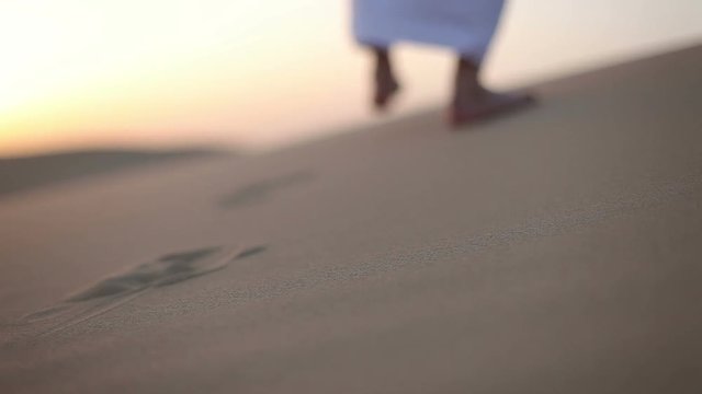 Weary wayfarer goes in the desert at sunset