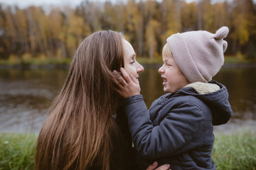 Mother and son having fun at the river bank in autumn