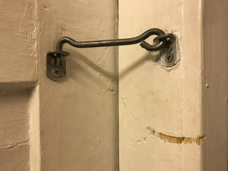The lock hook on the old wooden door. The door is closed. Background.