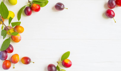 Fresh plums with leaves on white rustic wooden table. The concept of autumn harvest.