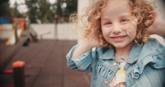 Girl with blue eyes and curly hair at kindergarten playground