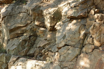 Granite rocks in the sun. Texture of granite stone. Background of natural material. Rocky rocks of ancient times. Minimalism