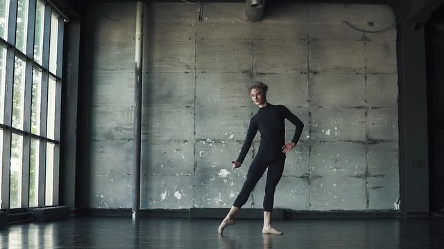 portrait of a male ballet dancer on a dark background. the dancer is spinning on tiptoe and moving beautifully. slow motion
