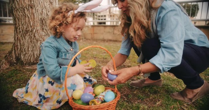 Little girl with grandmother enjoying Easter egg hunt in garden