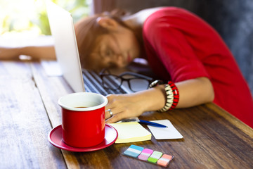 Fototapeta na wymiar close up coffee cup and Tried of business woman overwork sleeping,headache,stress which has tried work hard and headache out of time pressure in the office