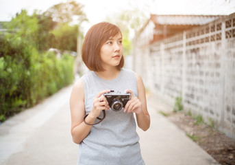 Young and beautiful Asian girl holding a retro film camera to take street photography