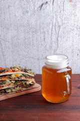 Beer and pizza. Pizza slices on a wooden board. Glass of light beer with foam on a wooden background. Favorite food set for men