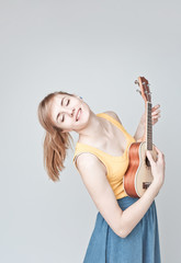 Attractive woman with light hair  plays ukulele on white background