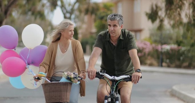 Happy mature couple having fun cycling together on romantic date