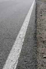 Obraz premium the cracked asphalt on the highway, a continuous strip and a part of a roadside