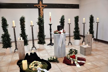 Eine Trauerfeier in der Kapelle, eine Urnenbestattung dekoriert mit Tauerkränzen und Kerzen für die Hinterbliebenen des Verstorbenen, eine rotes Herz als Symbol der Liebe im Vordergrund, 