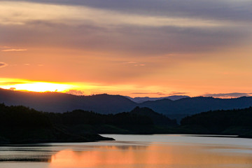 Fototapeta na wymiar Beautiful sunset in the lake with layers of the mountain.