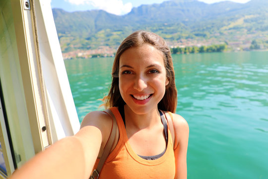 Selfie photo of young model woman on travel cruise vacation in orange tank top enjoying the evening on getaway holidays. Happy traveler vacations in Italy. 