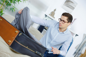 close up of businessman packing clothes into travel bag