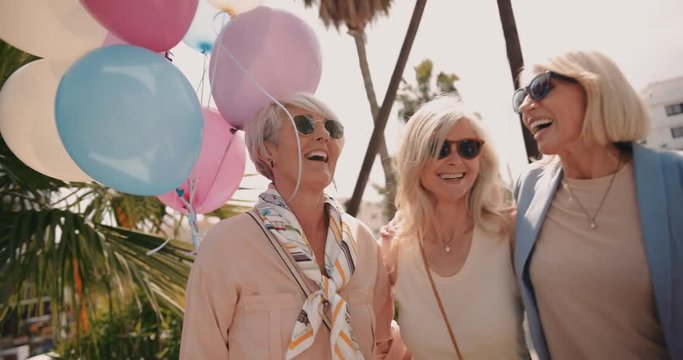 Female mature friends having fun in the city with balloons