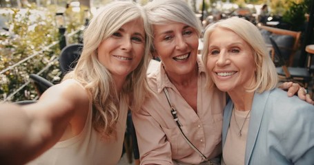 Mature friends having fun taking selfies at urban cafe - Powered by Adobe