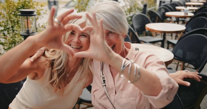 Happy mature women making heart shape with their hands