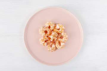 Fototapeta na wymiar Boiled shrimp on a pink plate. Macro. The concept of healthy eating. The background is white. Copy space. Horizontal shot. Top view.
