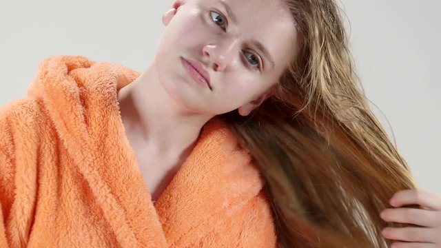 Teenage girl drying long hair after bath with hair dryer.