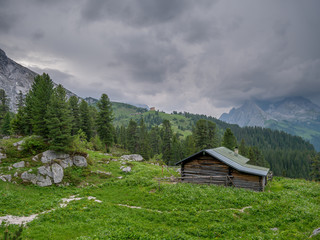 Fototapeta na wymiar Wooden cabin in the bavarian alps with stormy weather in the background