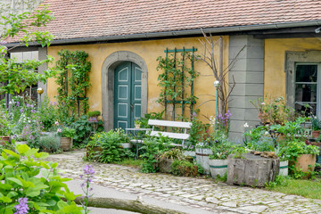 beautiful front garden with a white bench and flower tubs