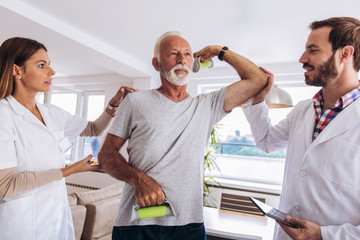Obraz premium Man having chiropractic arm adjustment. Physiotherapy, sport injury rehabilitation. Senior man exercises in center for chiropractic.
