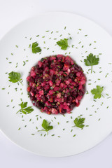 Salad with beets. Vinegret is a traditional Russian salad made from beets and vegetables in a white plate. The background is white. Top view. Copy space. Vertical shot.