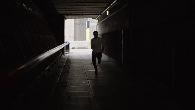 Man running in a tunnel speeds past the camera, in slow motion
