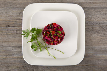 Salad with beets. Vinegret is a traditional Russian salad made from beets and vegetables in a white plate. Wooden background. Top view. Copy space. Horizontal shot.