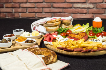 Close up of traditional Turkish breakfast served with Turkish donut (simit), cheese, salami, boiled egg, tomato, cucumber, fried potatoes and toasted bread