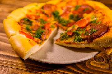 Ceramic plate with sliced homemade pizza on a wooden table