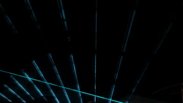 Abstract green and blue laser beams during an evening show on a dark background.