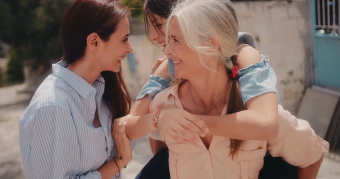 Grandmother, granddaughter and adult daughter having fun with piggyback ride