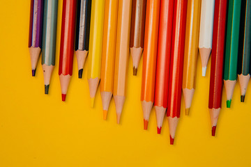 Color pencils on yellow background. Close up. Texture wood.