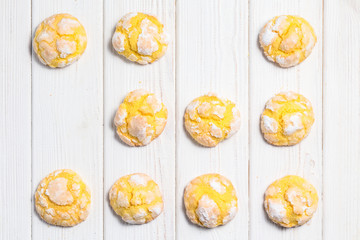 Homemade lemon crinkle cookies with powdered sugar icing. Cracked citrus biscuits on white wooden  background. Top down