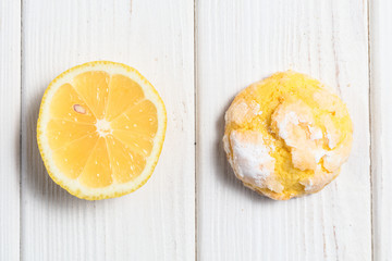 One Homemade lemon crinkle cookie with powdered sugar icing and slice of lemon.
