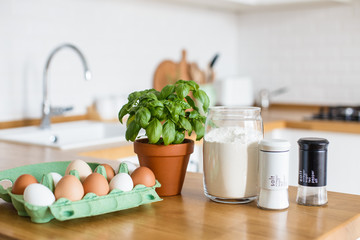 Baking ingredients placed on wooden table, pizza dough. Concept of food preparation. White kitchen on background