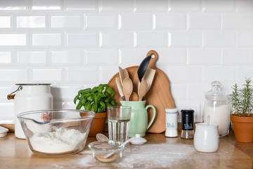 Baking ingredients placed on wooden table, pizza dough. Concept of food preparation. White kitchen on background