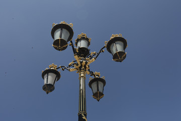 Fototapeta na wymiar Light post with blue sky background. Vintage outdoor street lights. Cast iron lamp Victorian large lantern. Lighting pole. Illumination. Electrical device