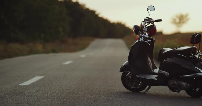 As the camera is moving by the road a little black motorbike is becoming visible while it stands still