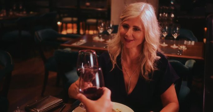 Happy senior couple toasting with wine on dinner date night