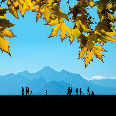 Silhouetted people walking on street over mountains and clear blue sky