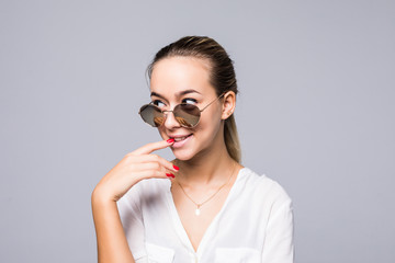 Beautiful young woman in elegant sunglasses smiling over gray background