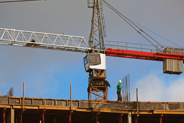 Fototapeta na wymiar builder in a helmet on a construction site against a tower crane