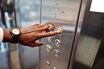 Close up photo of african american man hand with watches at elavator or modern lift, pushing button. © AS Photo Family
